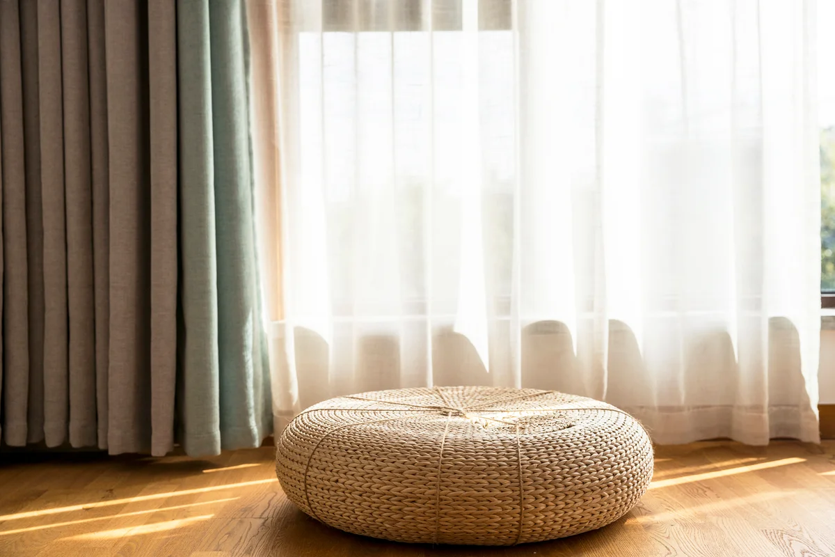 Straw cushion on the floor and linen drapes on window