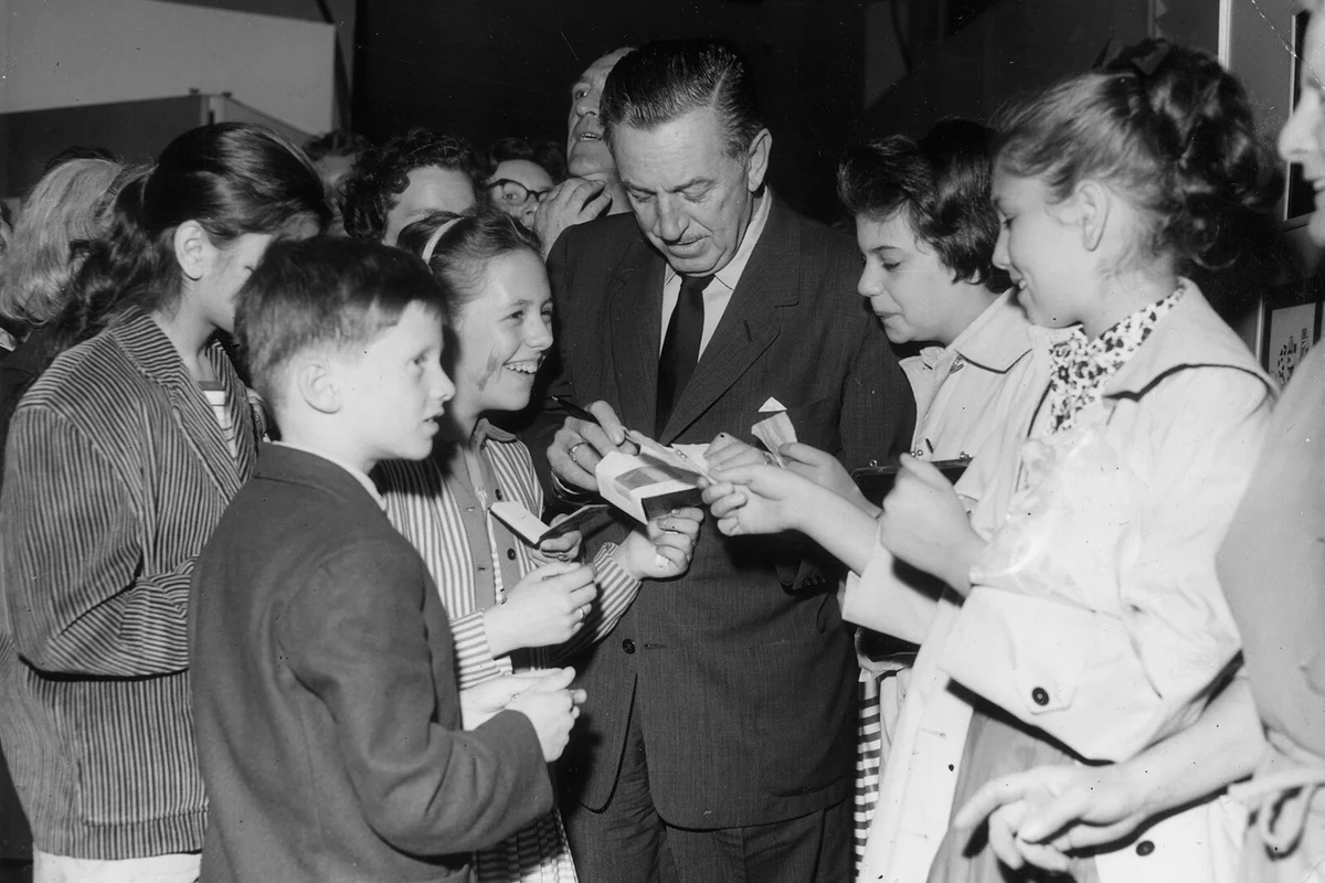 American cartoonist and producer Walt Disney (1901 - 1966) signs autographs for a group of smiling young fans | Getty Editorial Use