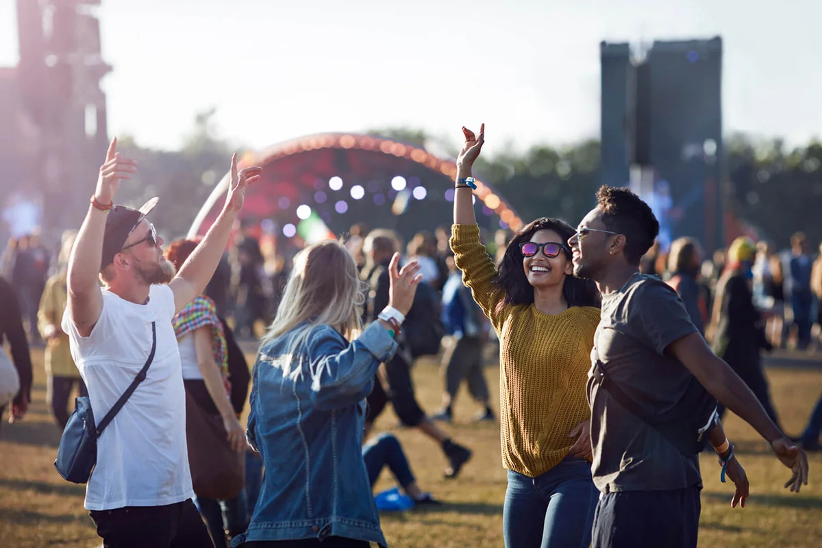 Friends dancing at festival with arms in air