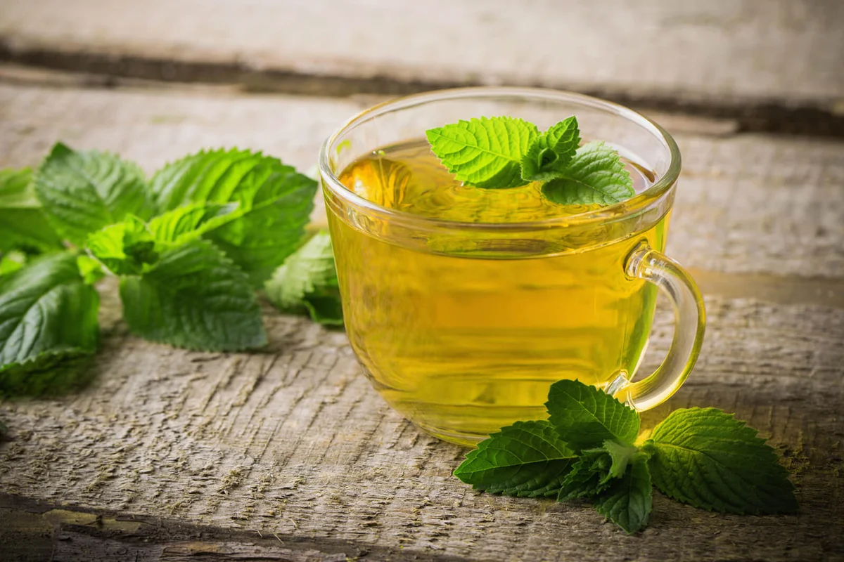 Cups of tea with mint on wooden
