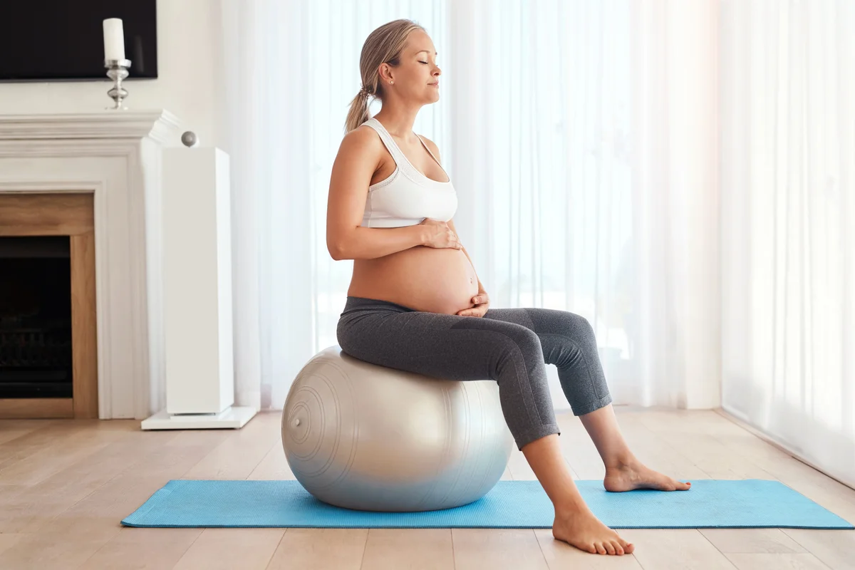 Pregnant woman working out with an exercise ball at home