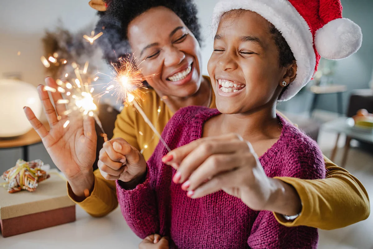 mother and daughter holding New Year's sparklers at home