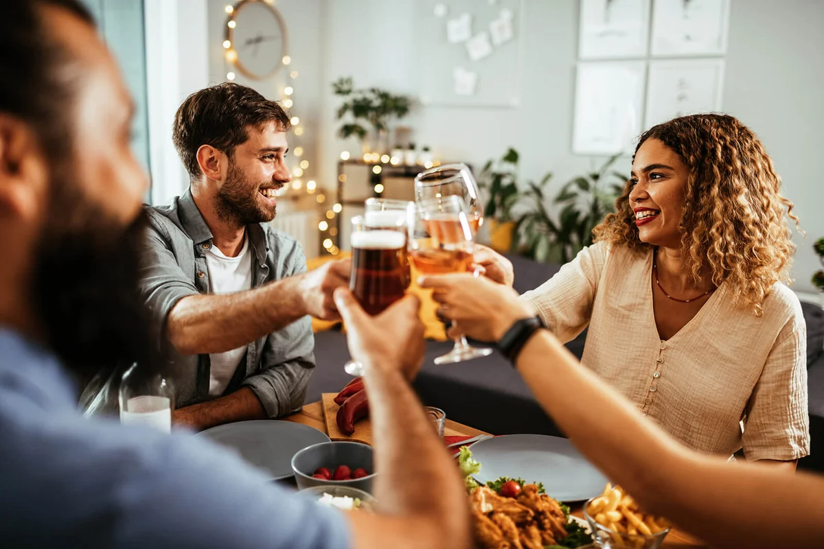 Friends and family eating Thanksgiving dinner and drinking wine