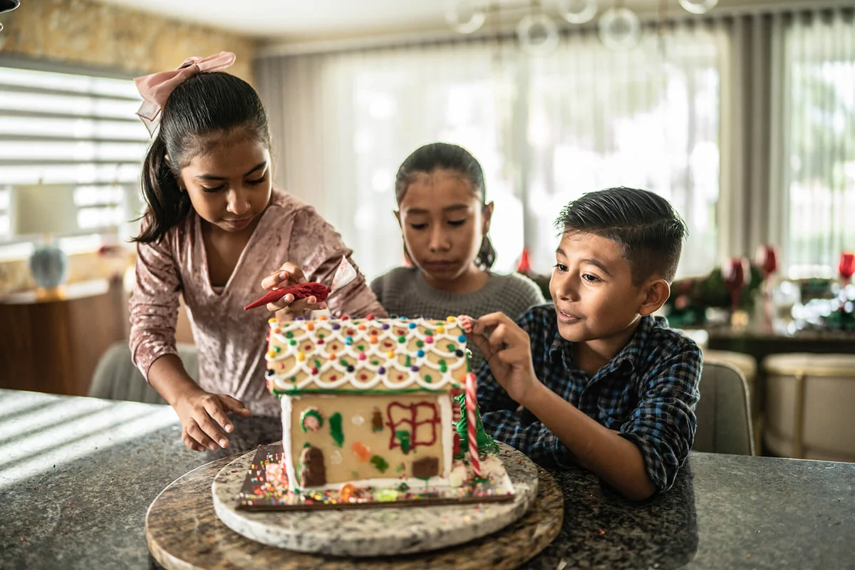 Siblings decorating gingerbread house
