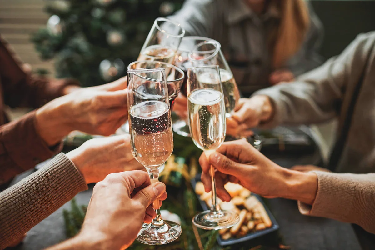 friends clinking champagne glasses while enjoying Christmas dinner