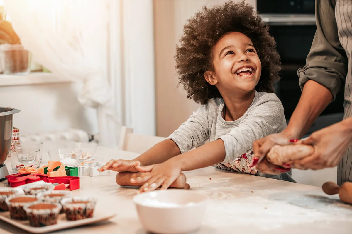 girl making cookies for Christmas with her mom