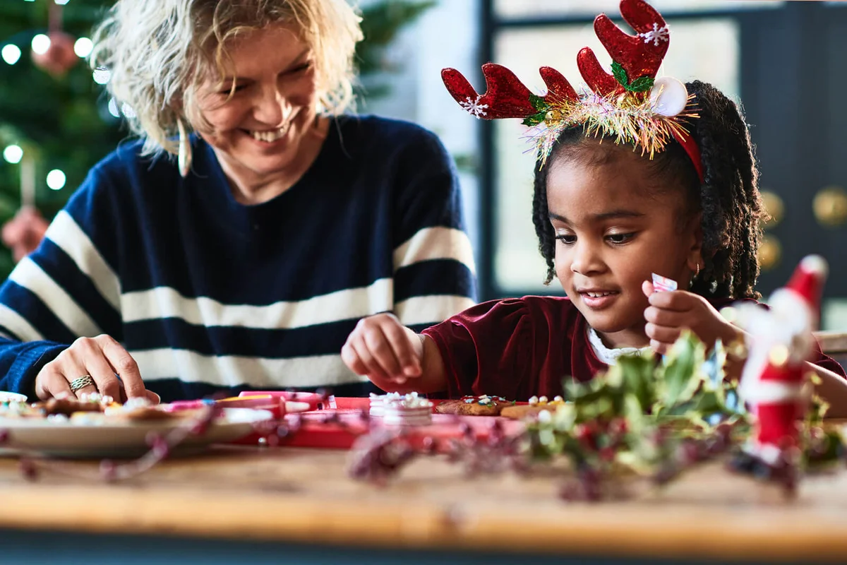 Grandmother helping granddaughter decorate Christmas cookies