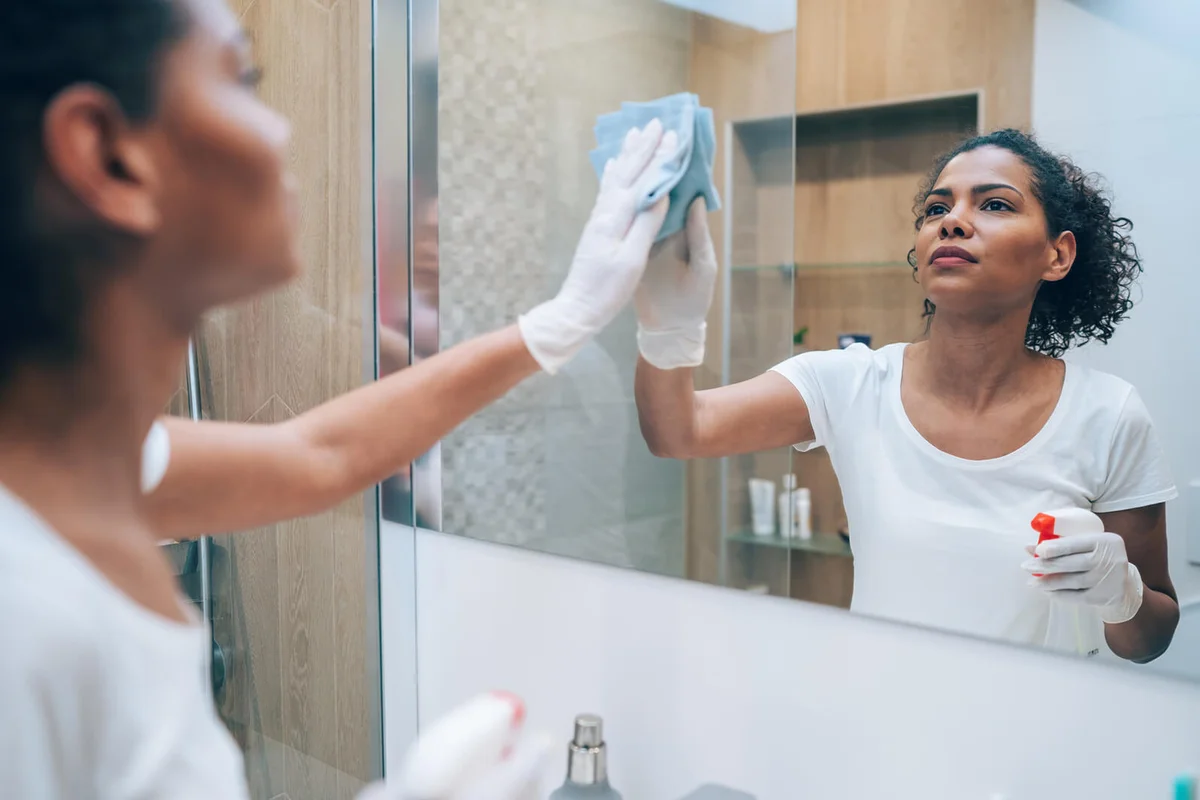 Woman cleaning bathroom mirror