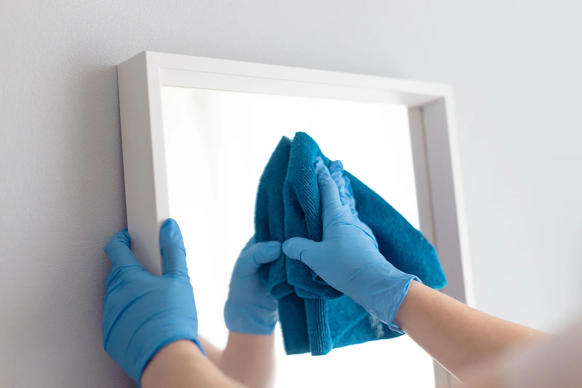 Woman cleaning mirror with rag