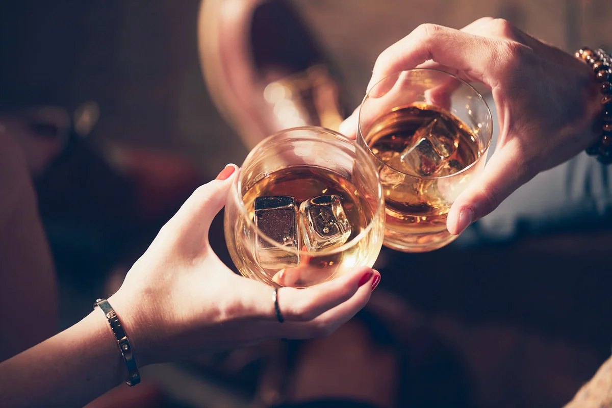 Cropped hands of friends toasting drinks in glass