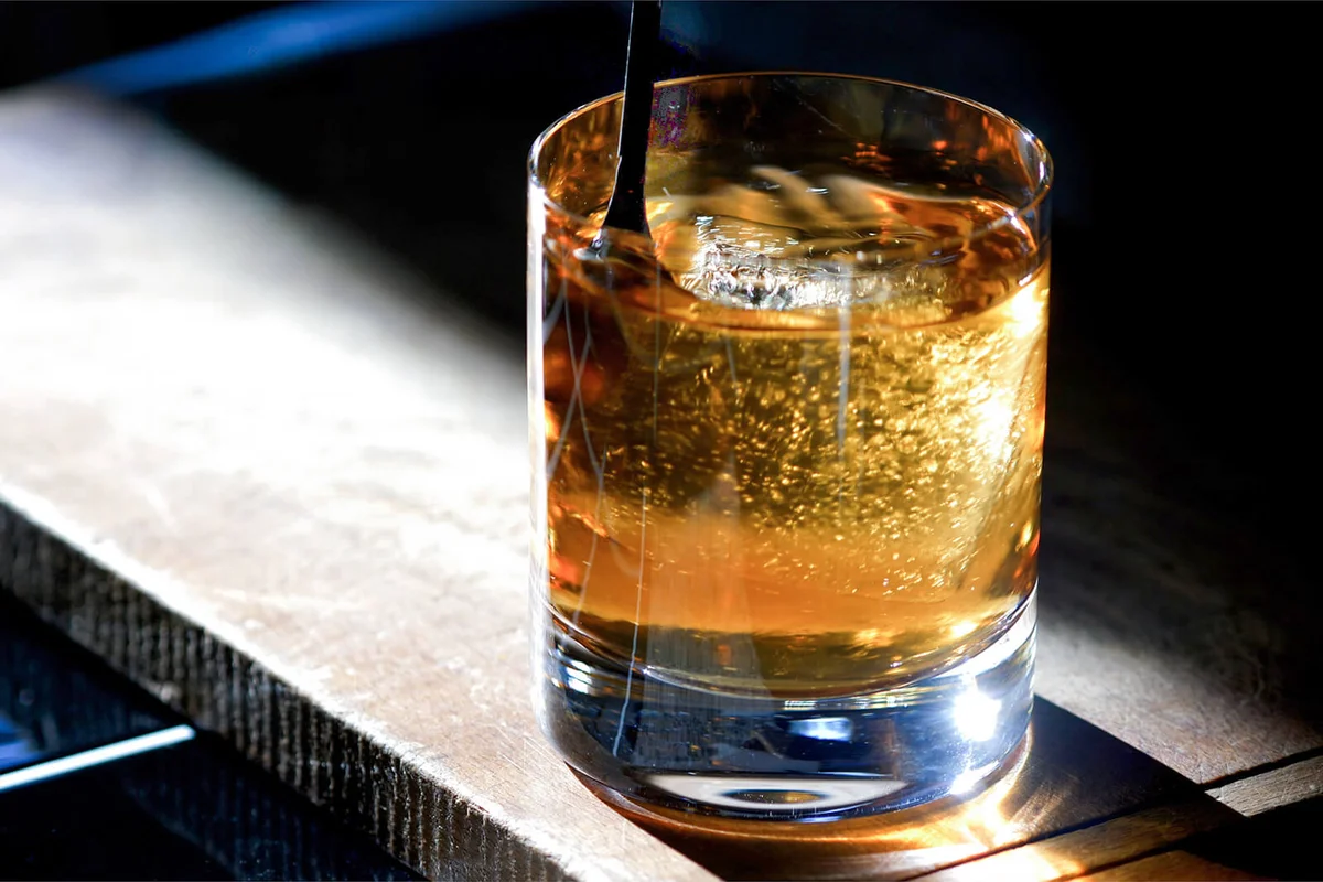 Classic Prohibition Manhattan Cocktail in Old Fashioned Rocks Glass being stirred