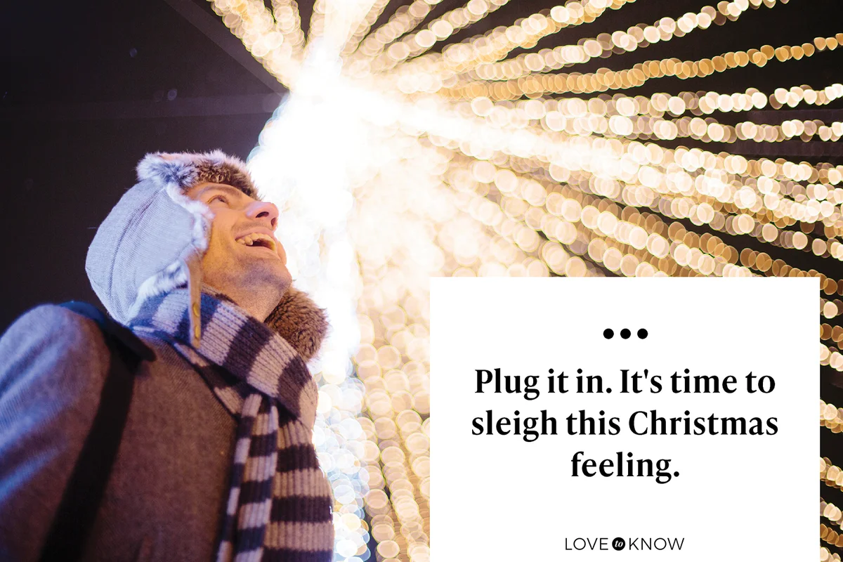 Young man laughing against Christmas lights