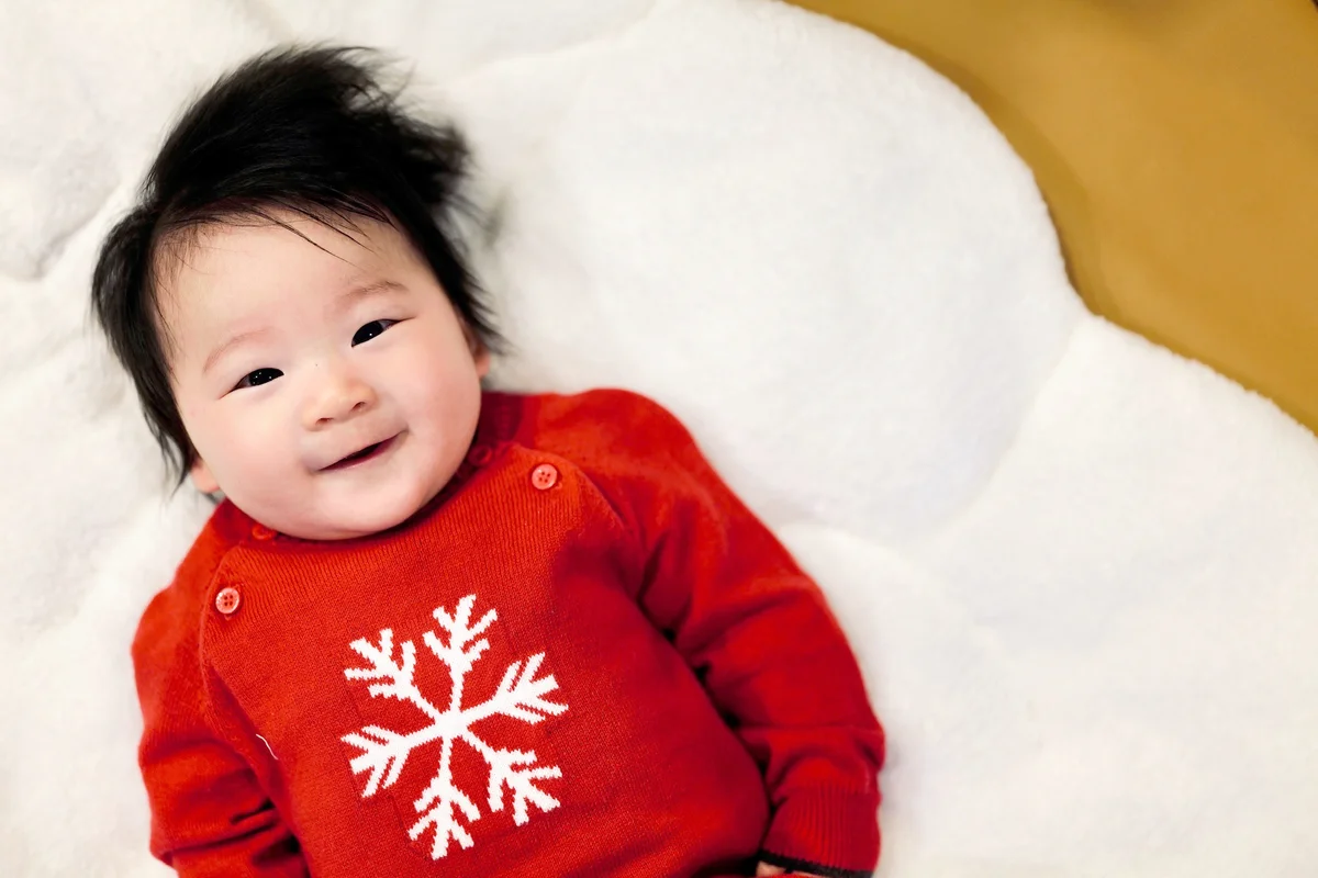 Cute baby boy lying on bed with winter sweater