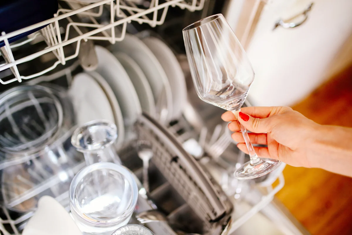 Woman's hand putting wine glass in the washer