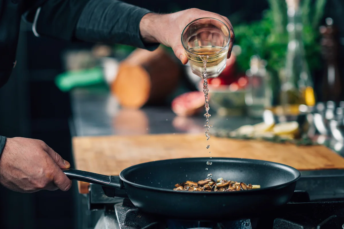Chef Pouring White Wine into Frying Pan with Sliced Shiitake Mushrooms