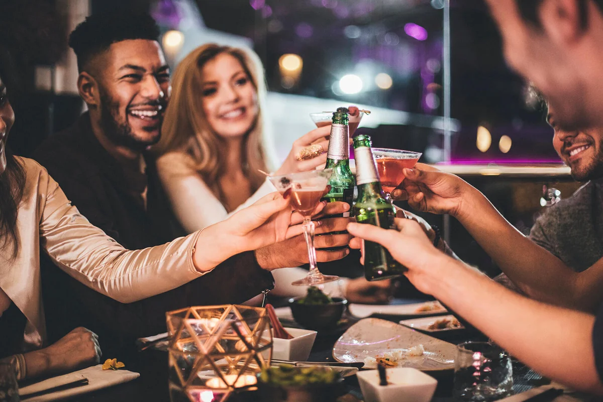Group of friends clinking glasses while enjoying an evening meal