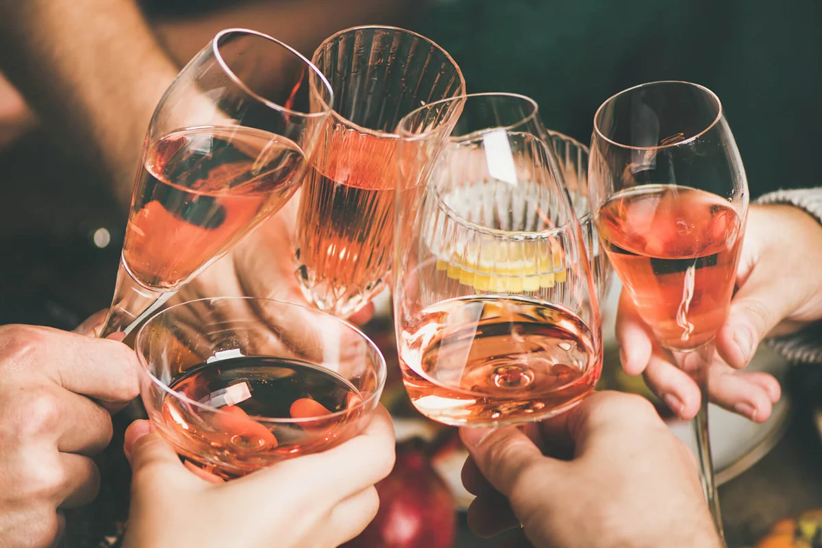 Friends clinking glasses with rose wine at New Year