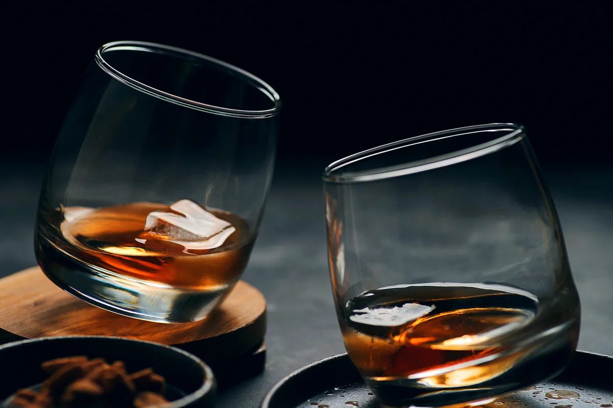 The glass of whisky on the table with dark background