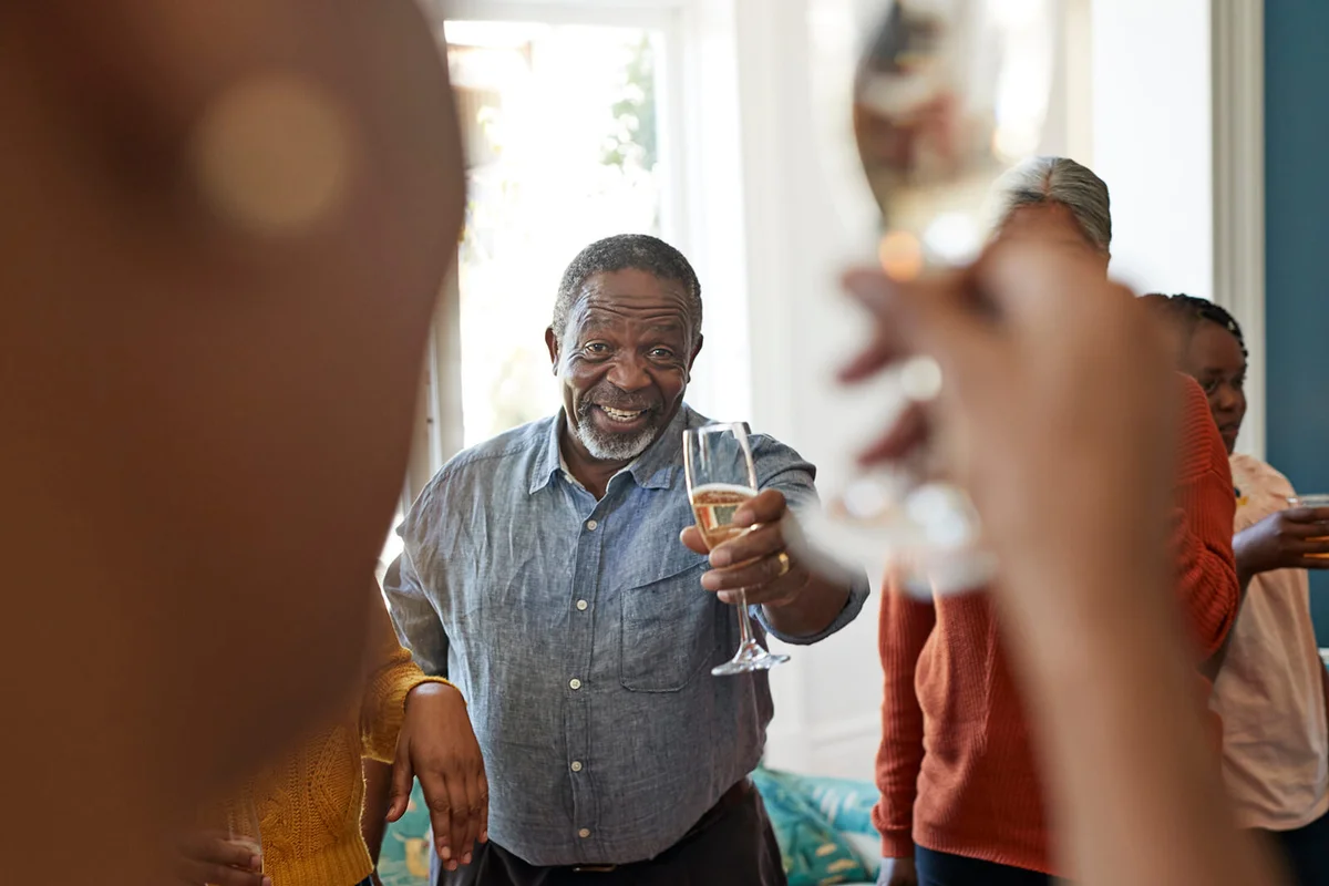 Portrait of cheerful senior man showing champagne