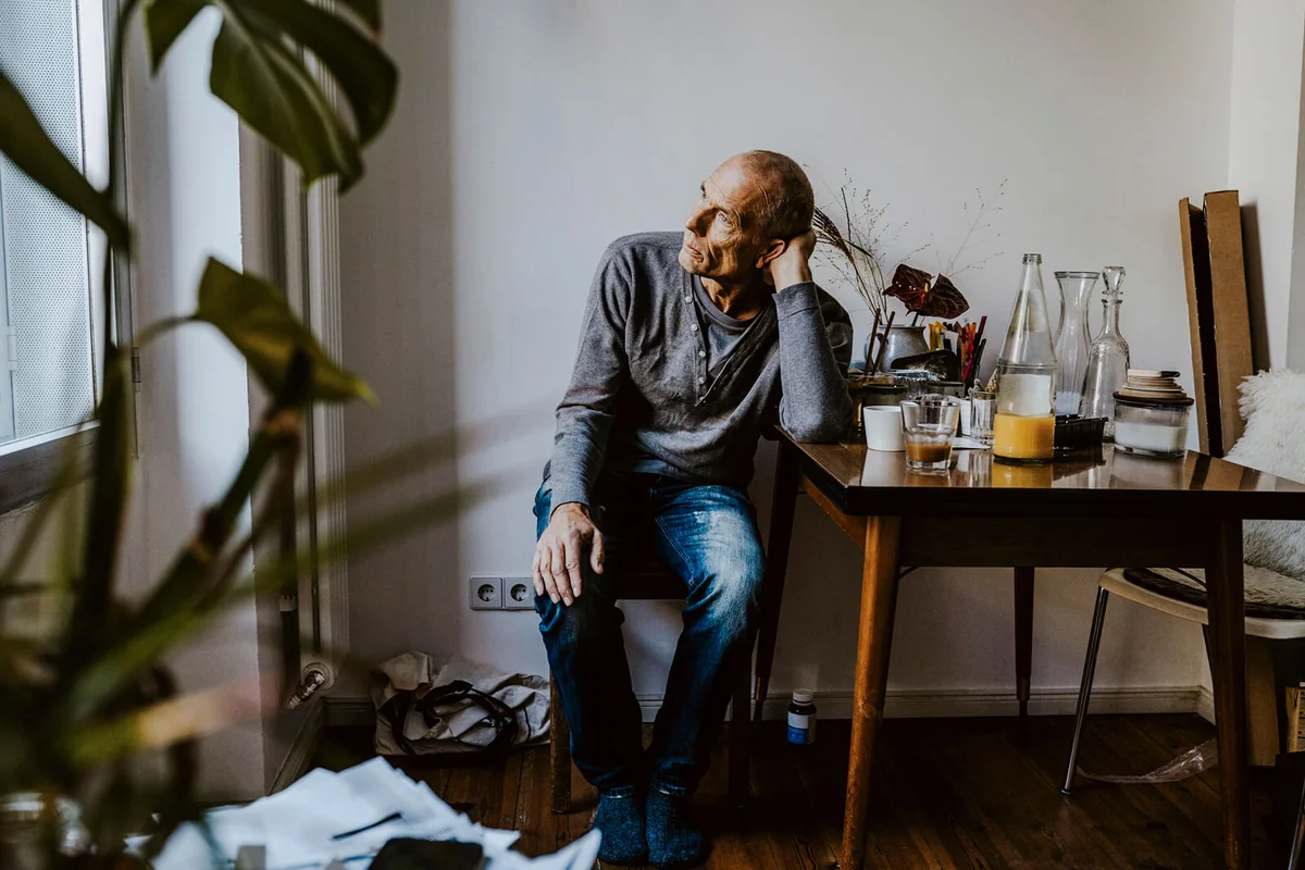 Thoughtful senior man sitting on chair in living room