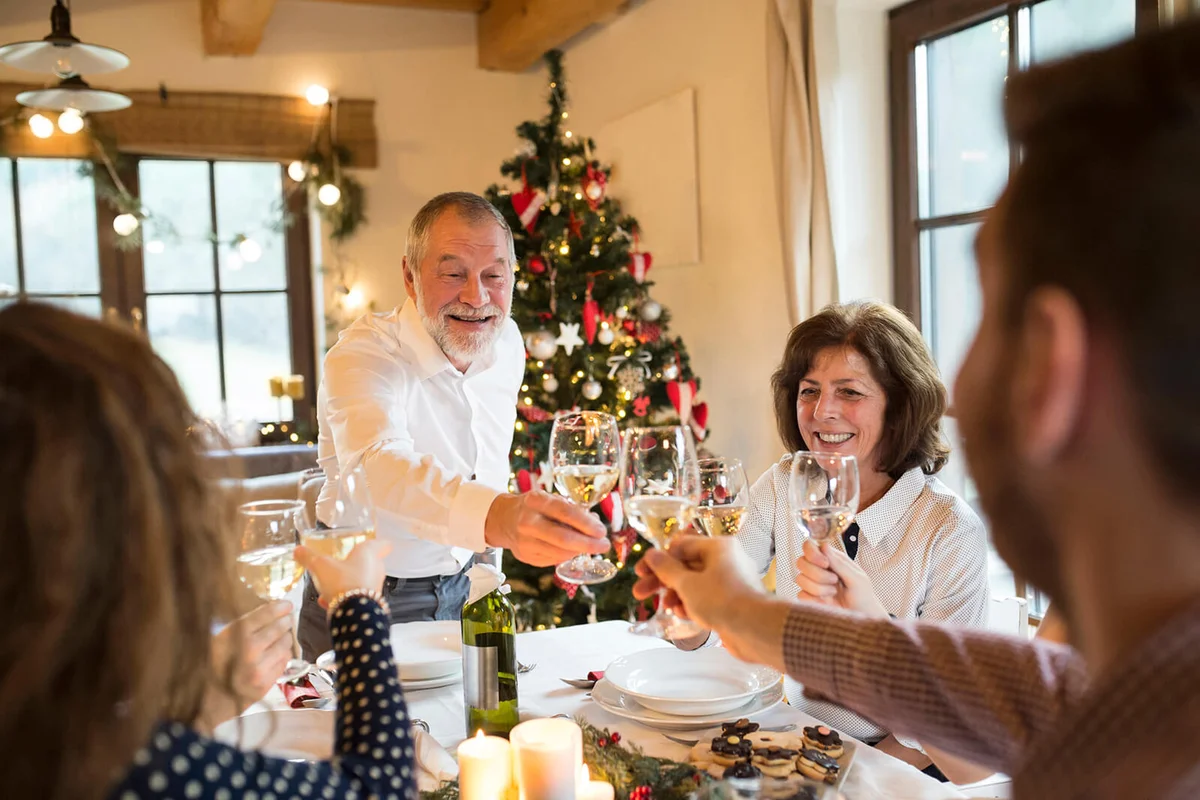 Senior man clinking glasses with family at Christmas dinner