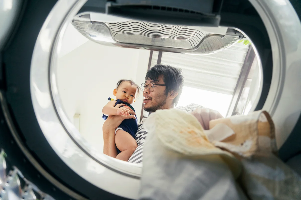 Father embracing daughter putting a dirty apron in the washing machine