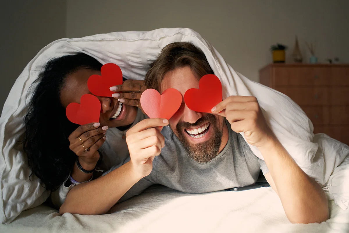 Young happy couple in bed with hearts in the eyes