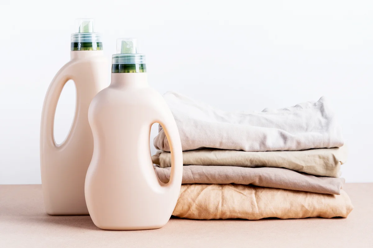 Stack of folded clean clothes with Eco bottles of detergent