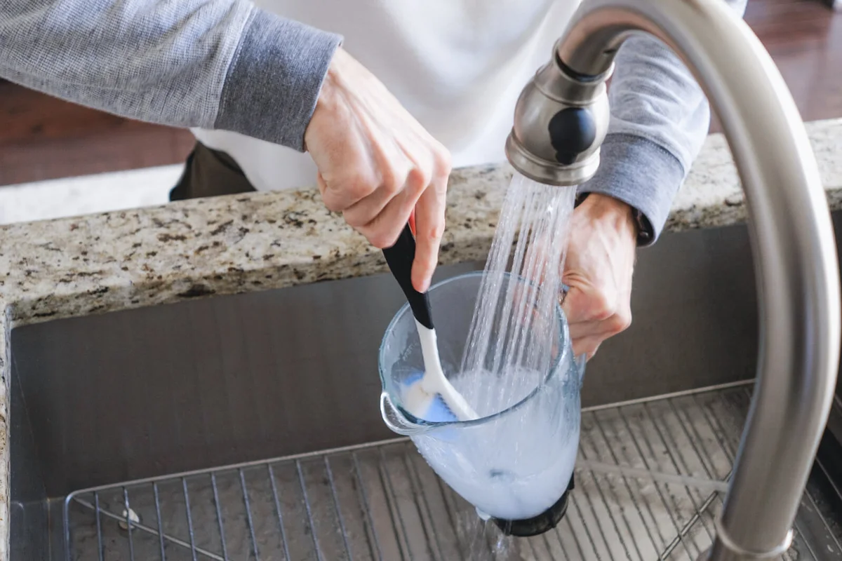 Man Washes Blender Jar in Kitchen Sink