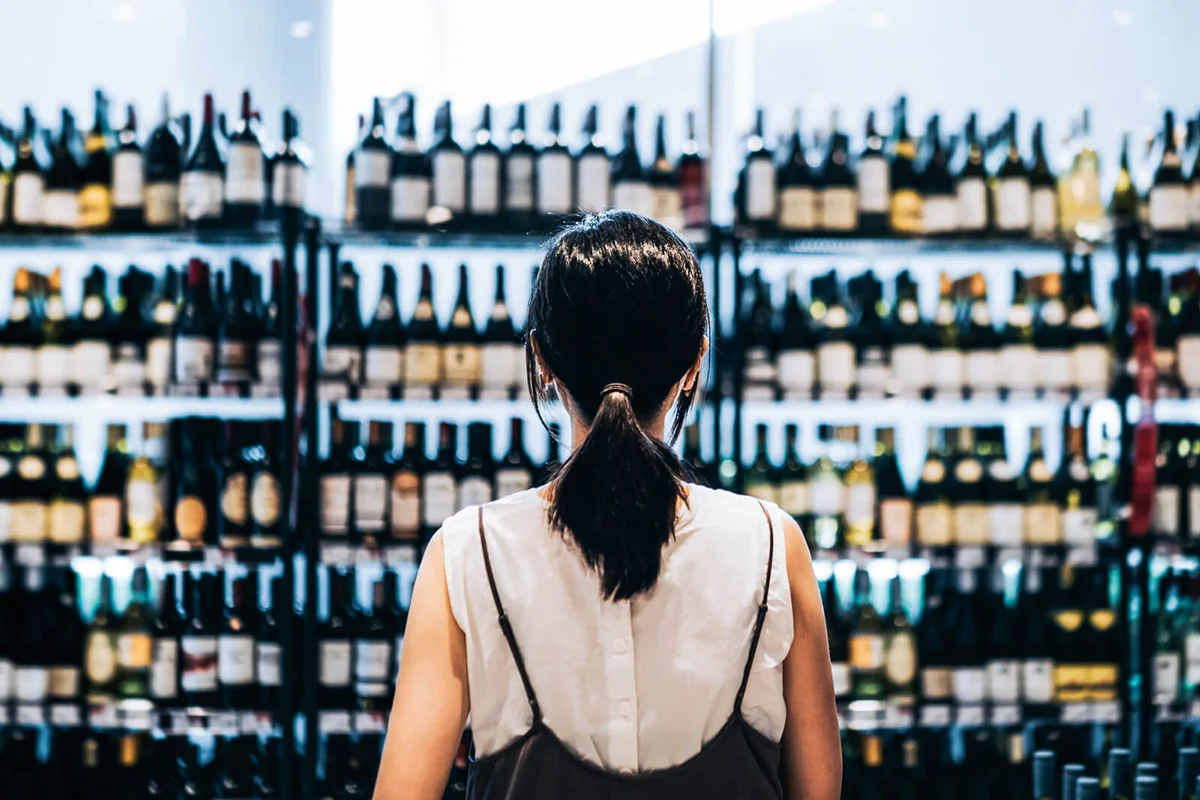woman grocery shopping for wines in a supermarket