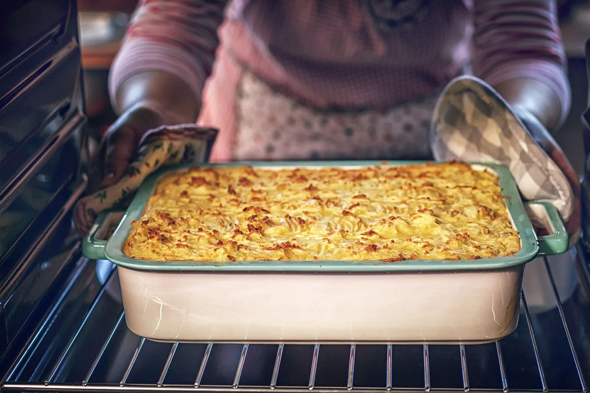 Woman placing casserole in the oven