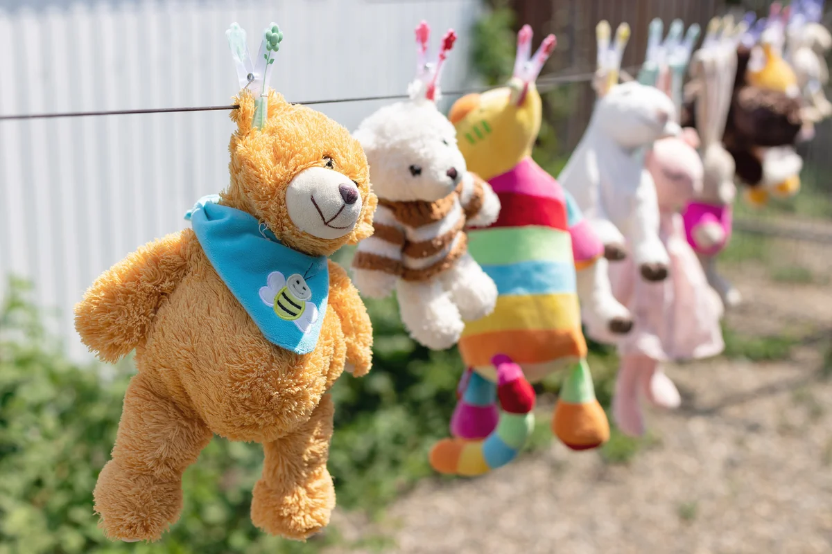 Various plush toys hanging from the clothesline in the backyard