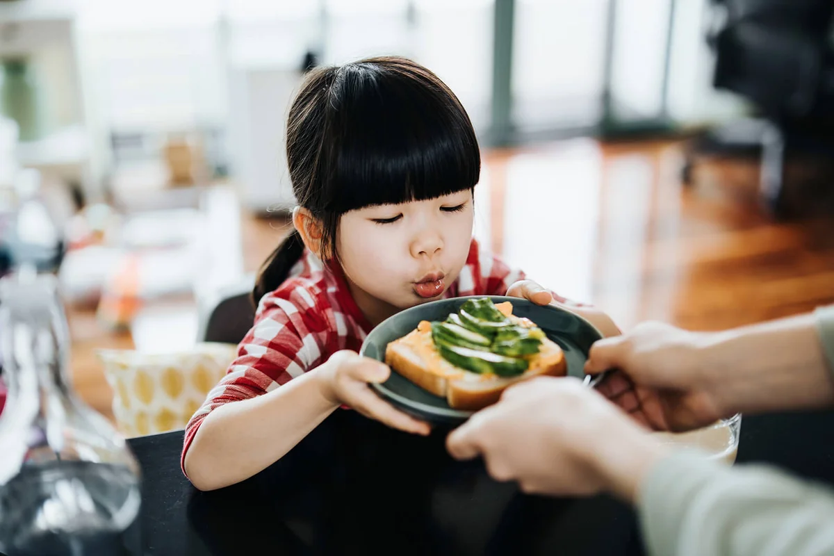 Lovely little Asian girl sitting at the table in kitchen