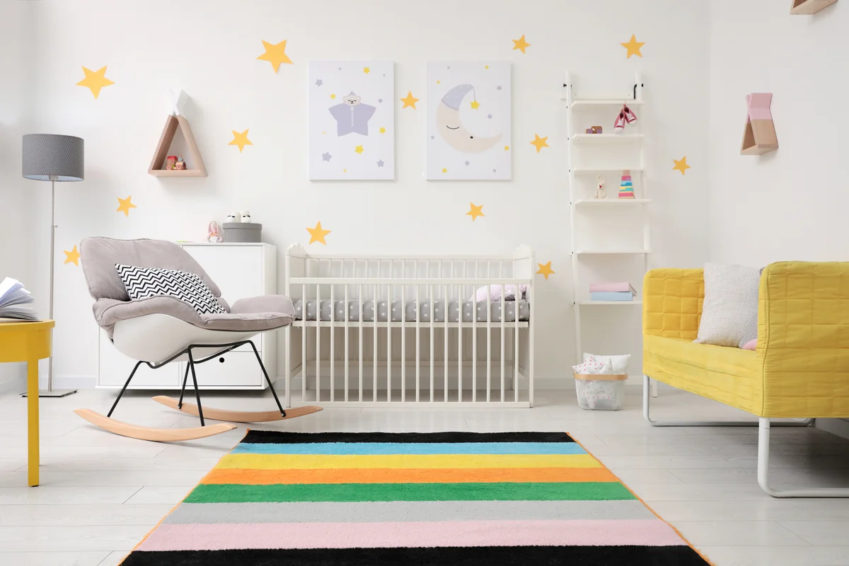 Stylish baby room interior with crib, rocking chair and sofa