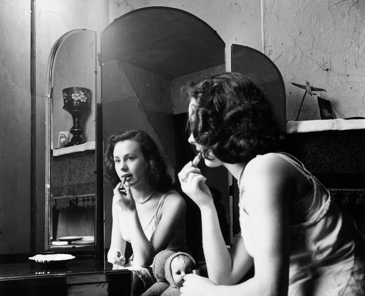 Sitting at her dressing table, sixteen year old hairdresser Betty Burden applies her lipstick