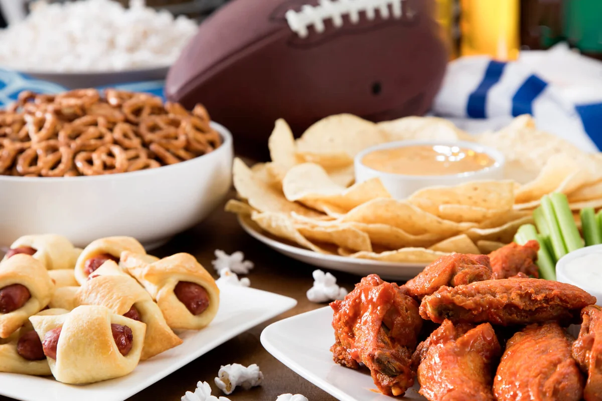 Hot wings, nachos, pigs in a blanket, beer, and popcorn, a tailgate party spread