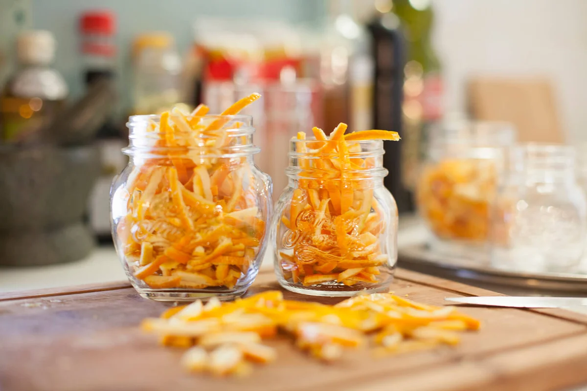Jars on kitchen counter filled with thinly cut orange zest