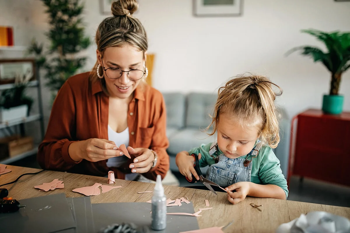 Mother and daughter making flowers of paper at home