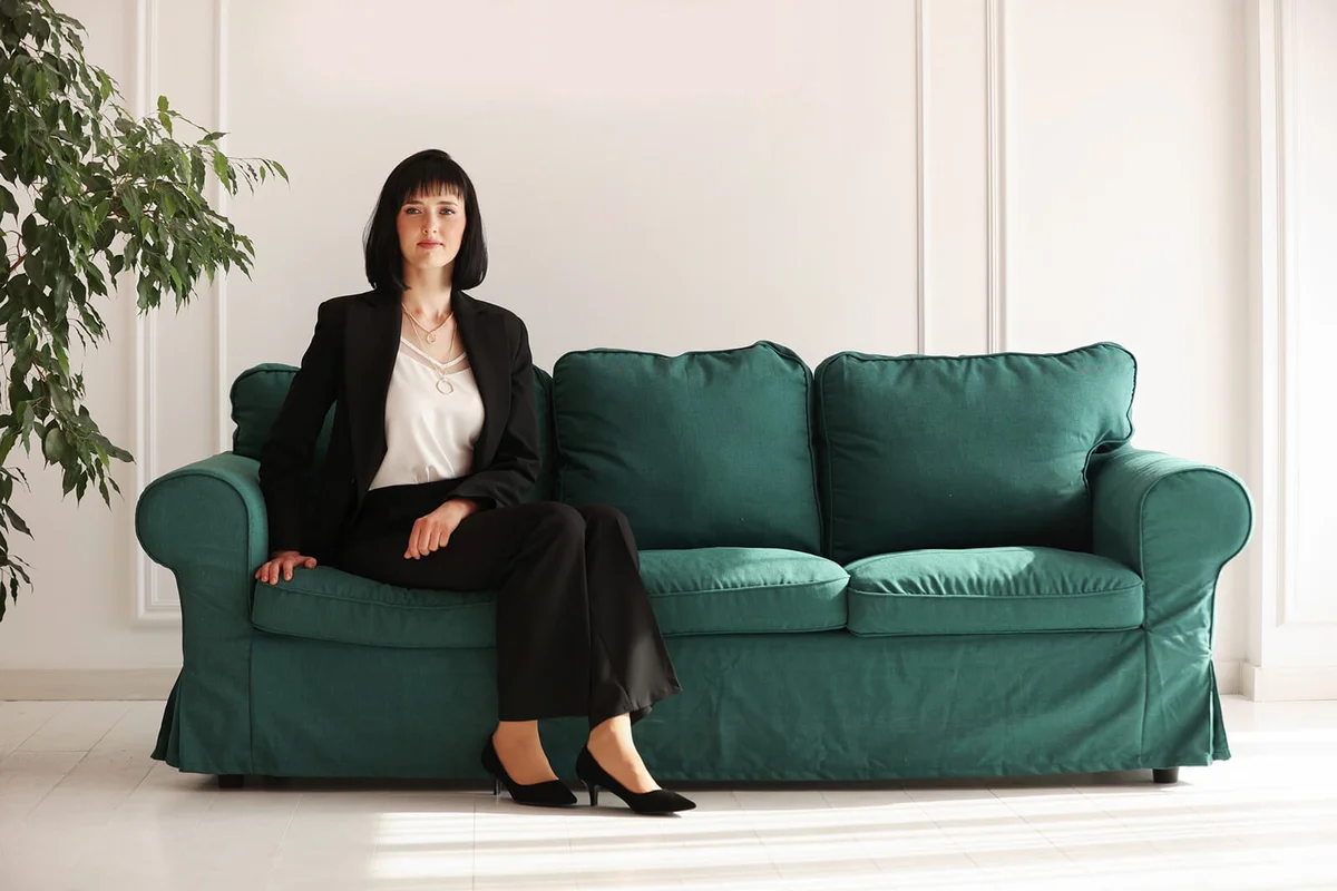 businesswoman in suit sitting on the edge of a stylish green sofa