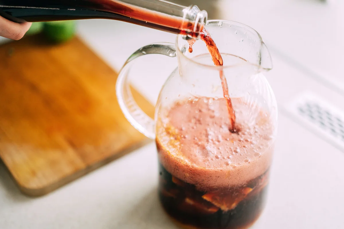 Pouring sweet red wine into a glass cocktail jug