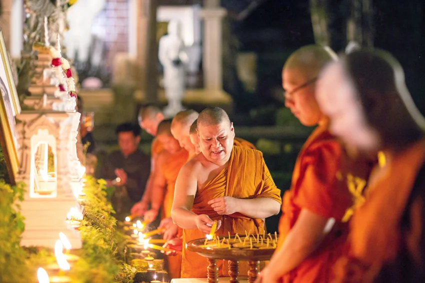 Thai Buddhist monks light candles during a religious ceremony