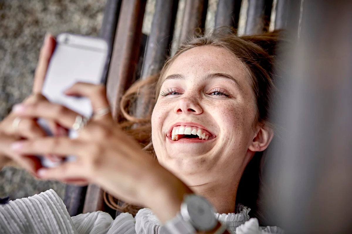 Woman laughing while using a smartphone for texting