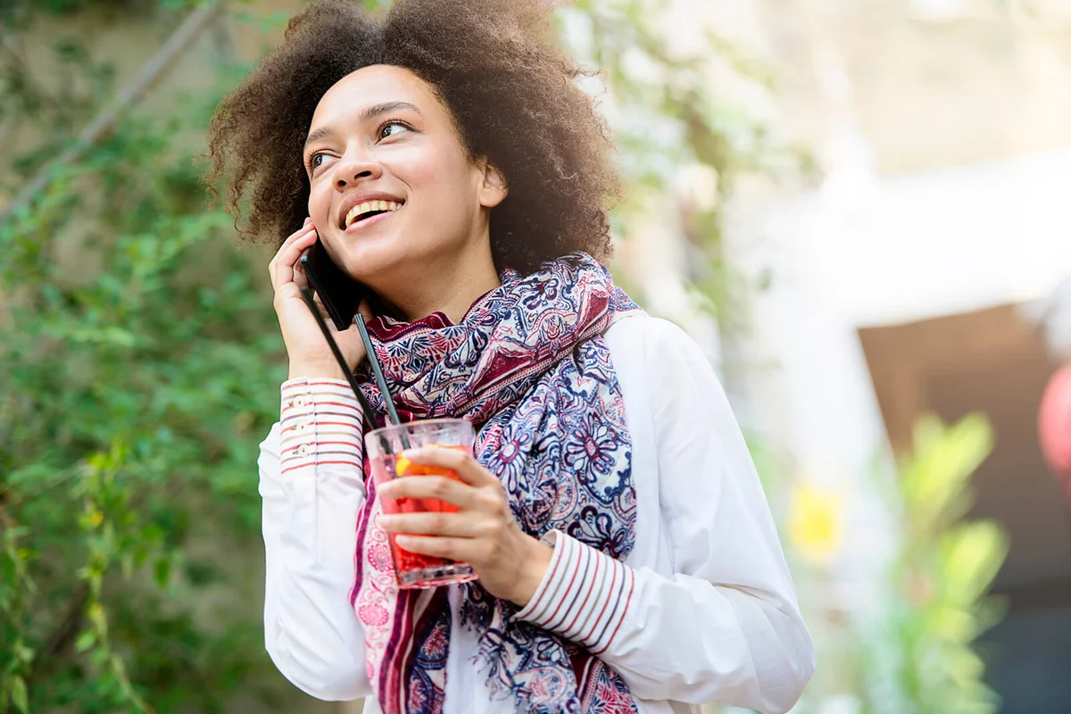 Beautiful girl with fruit cocktail using smartphone