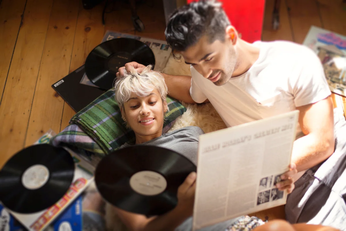Couple looking at vinyl records while lying on floor