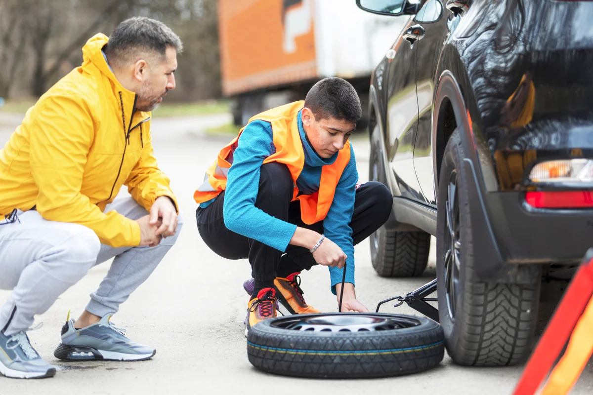 Father showing his son how to change tire