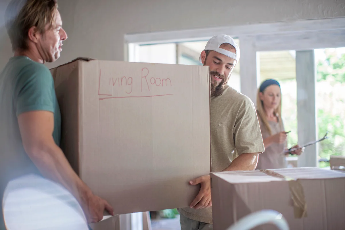 Movers carrying cardboard box into new house