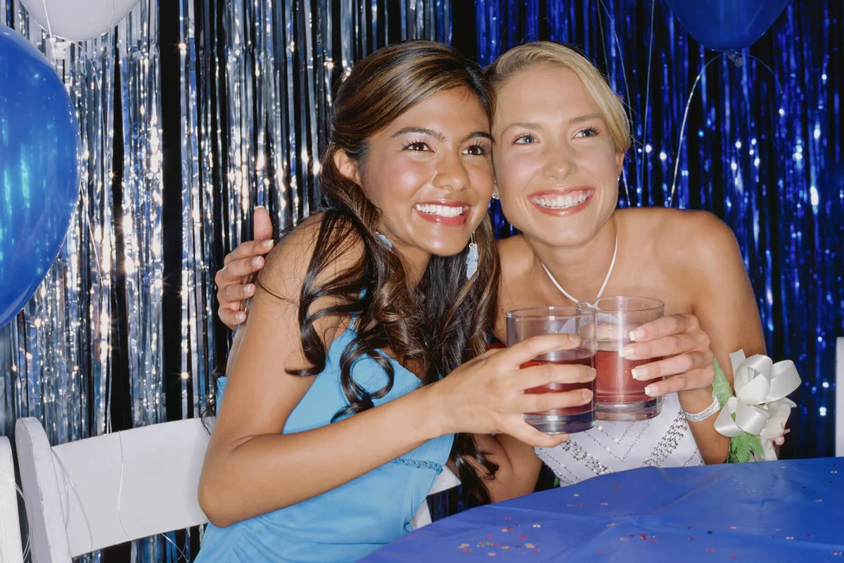 two teenage girls holding glasses of punch