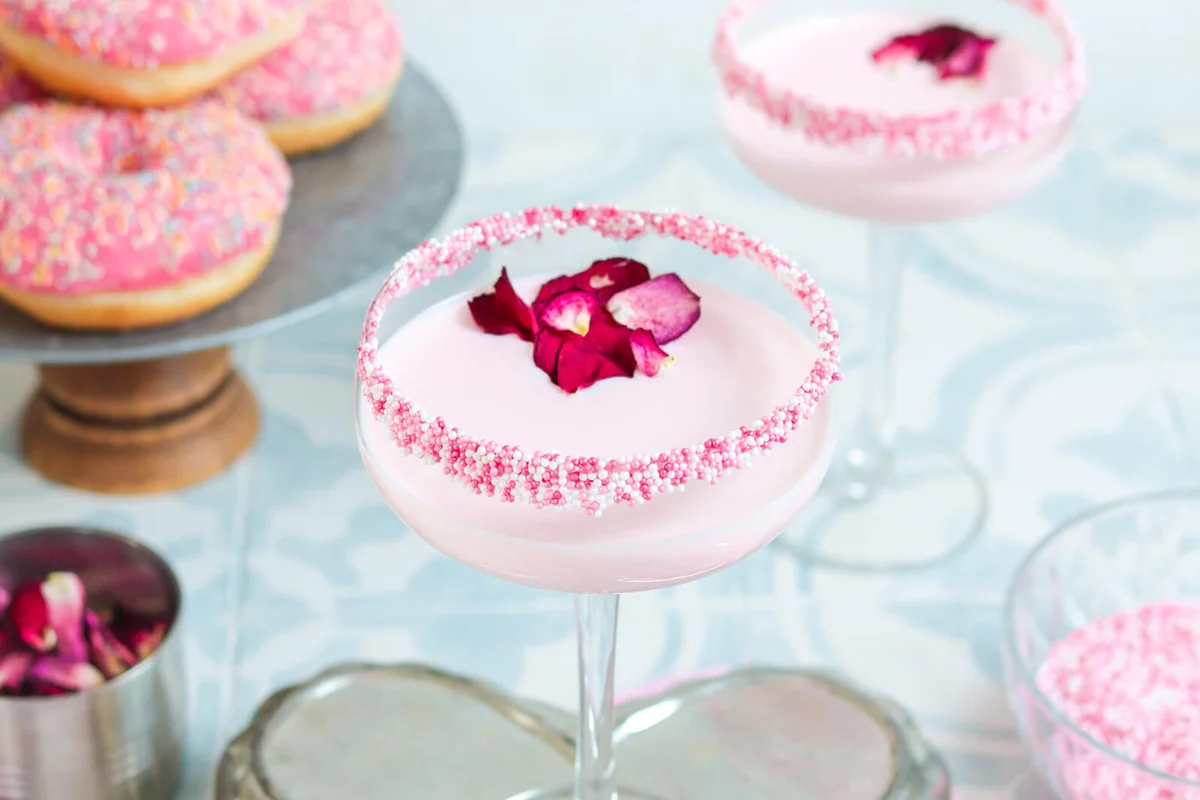 Pink strawberry cream Cocktail Drink with sugar sprinkles and rose petals