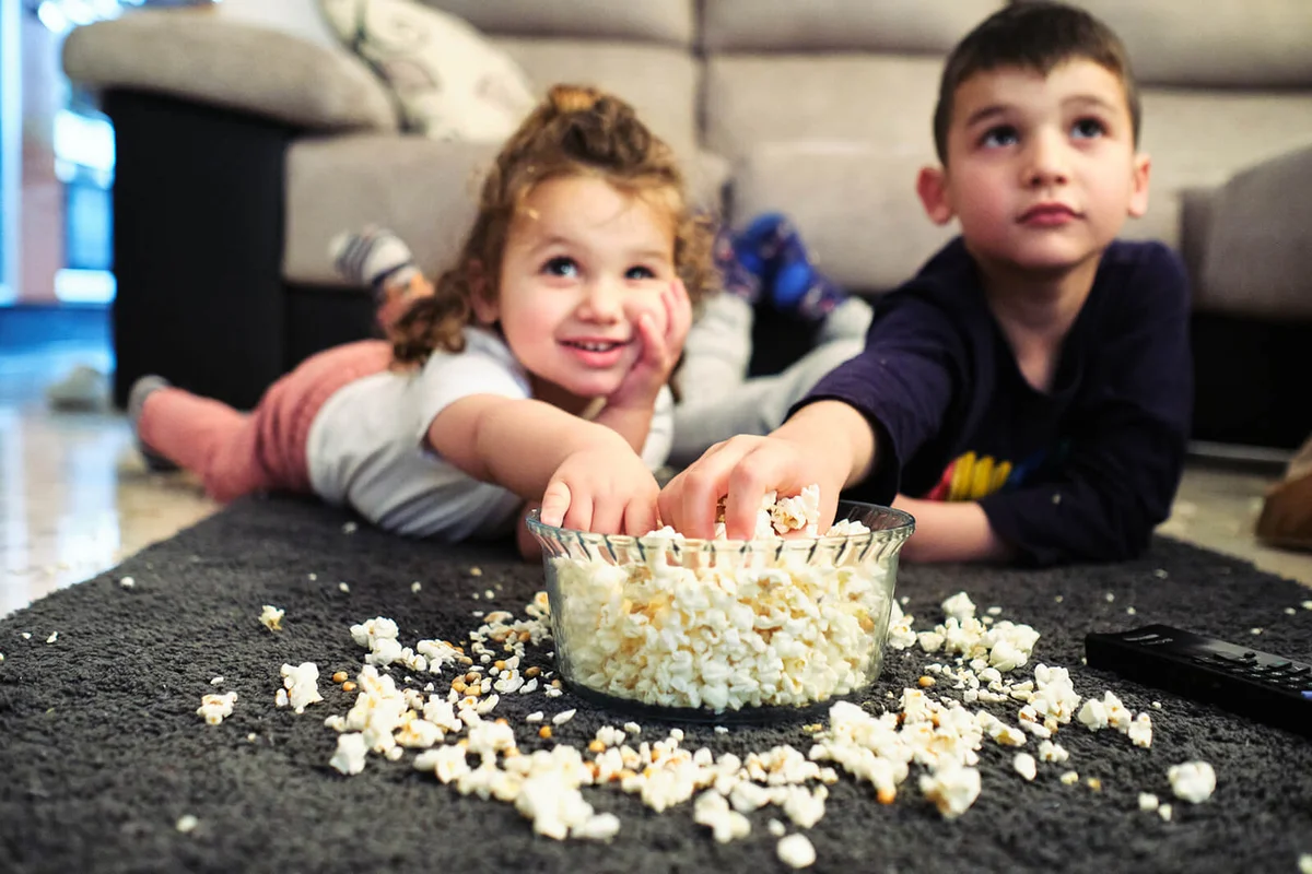 Siblings watching a home movie while eating popcorn