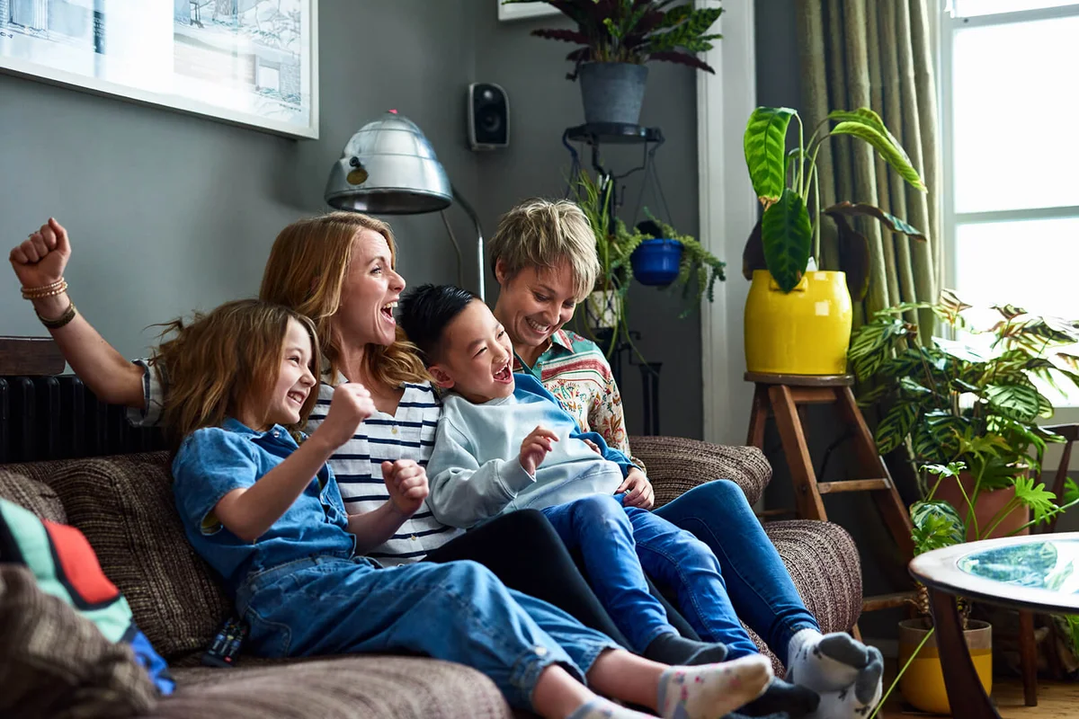 Cheerful family with two mums watching tv at home